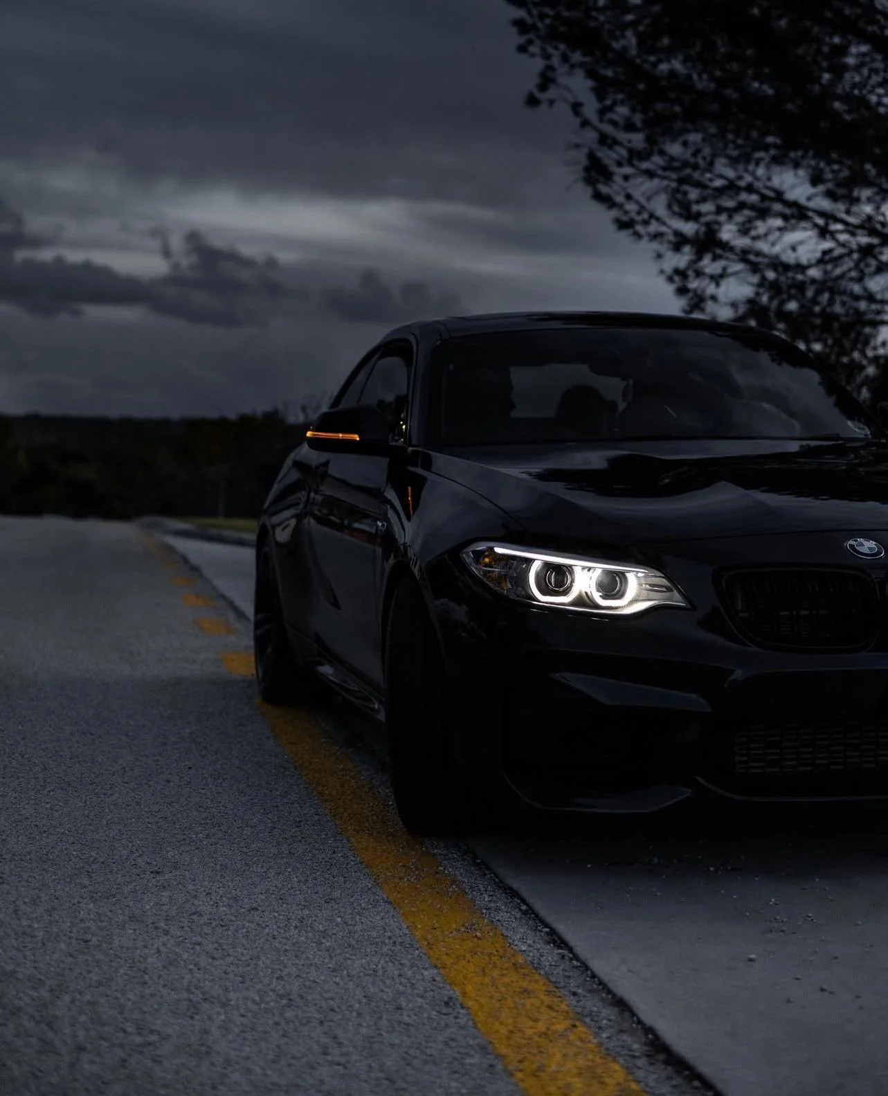Black BMW M2 on a moody road at dusk