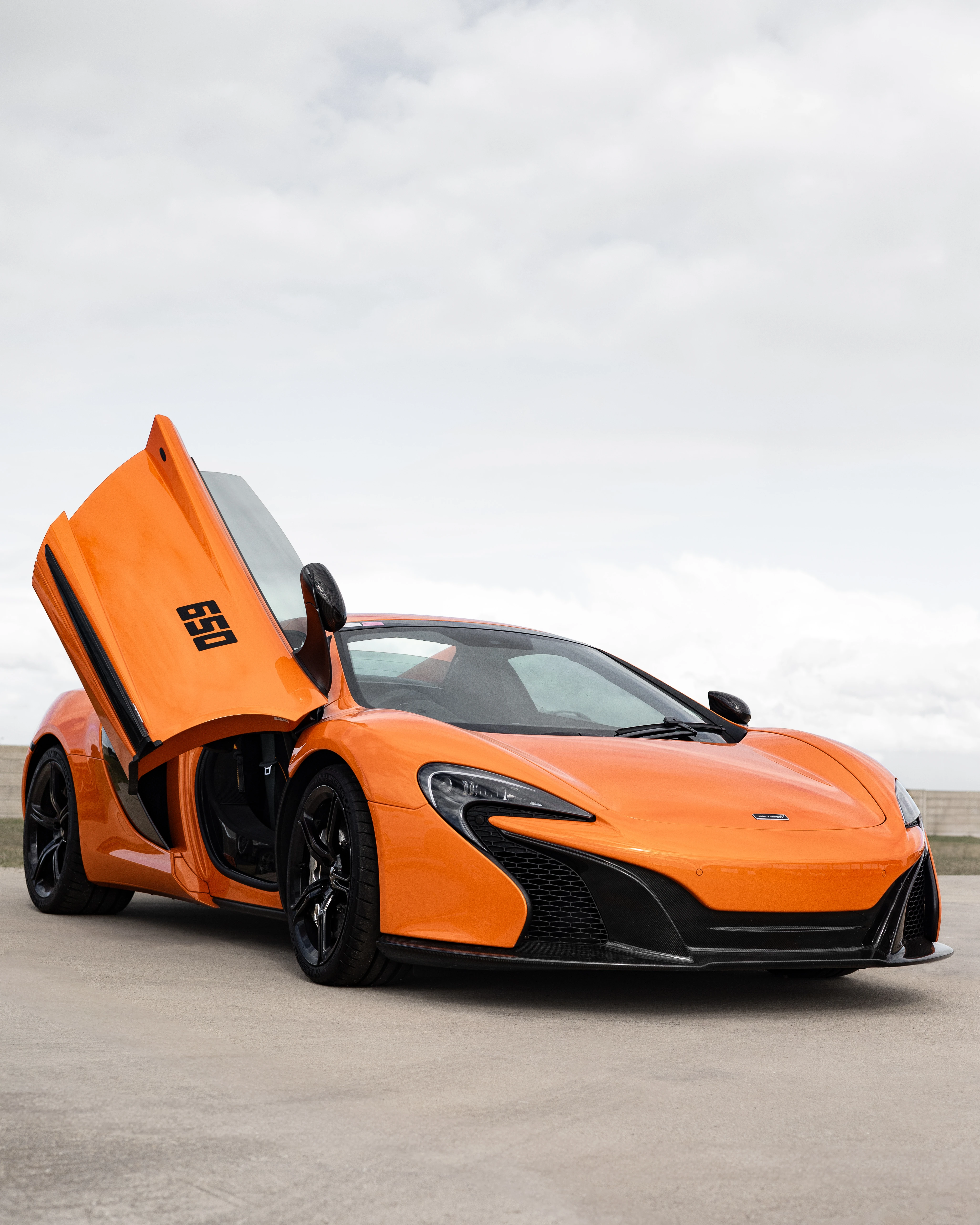 Orange McLaren 650S front three-quarter with doors up on rooftop