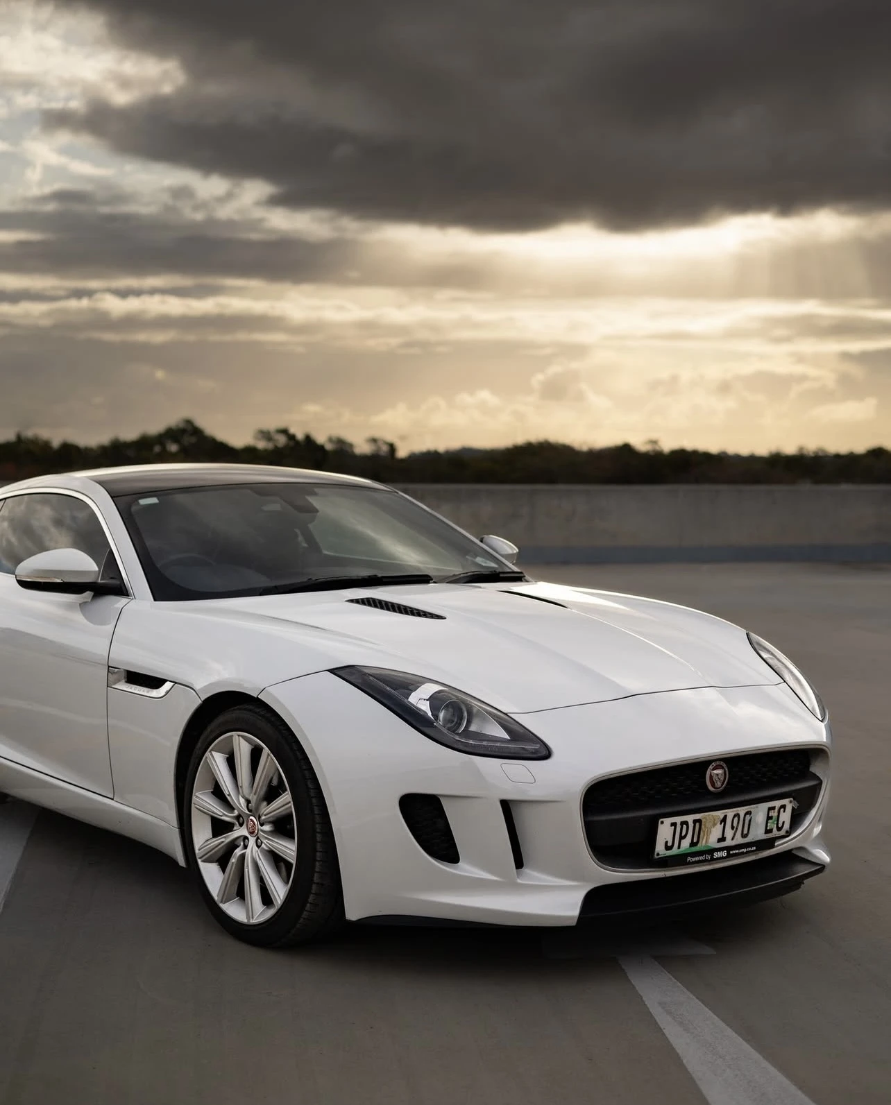 White Jaguar F-Type front three-quarter on rooftop with dramatic sky