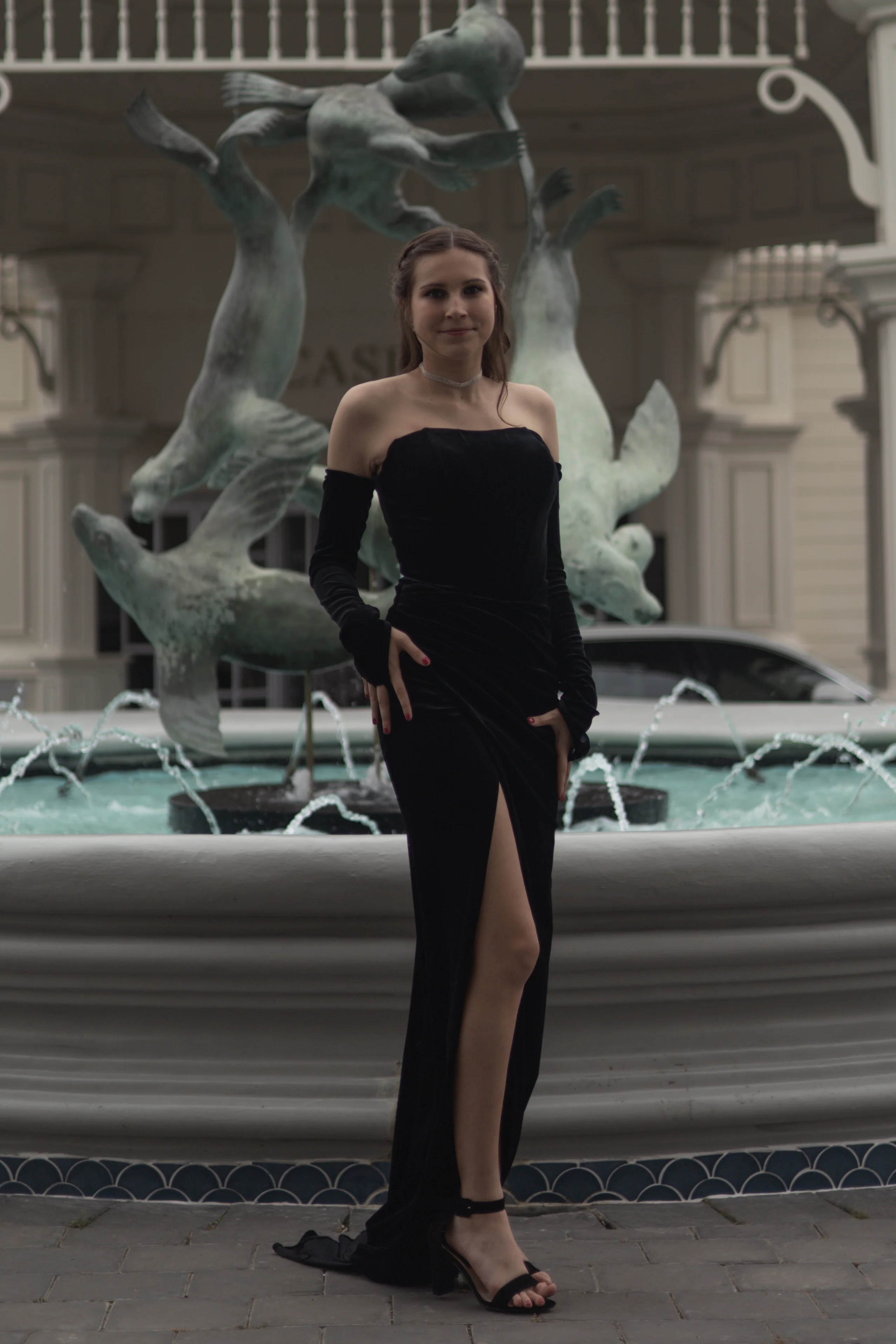 Woman in black off-shoulder dress posing at ornate fountain