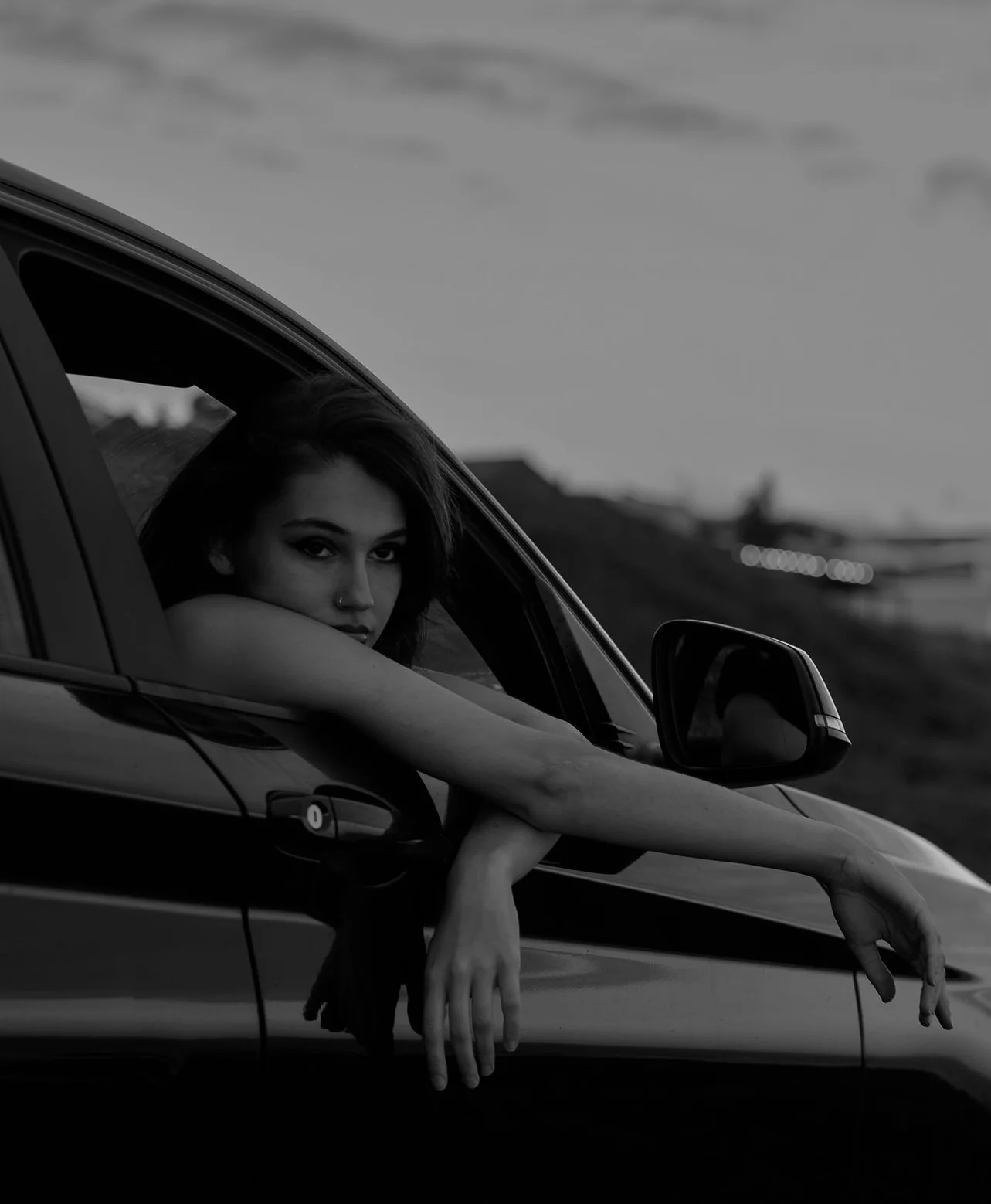 Woman leaning out of car window in black and white